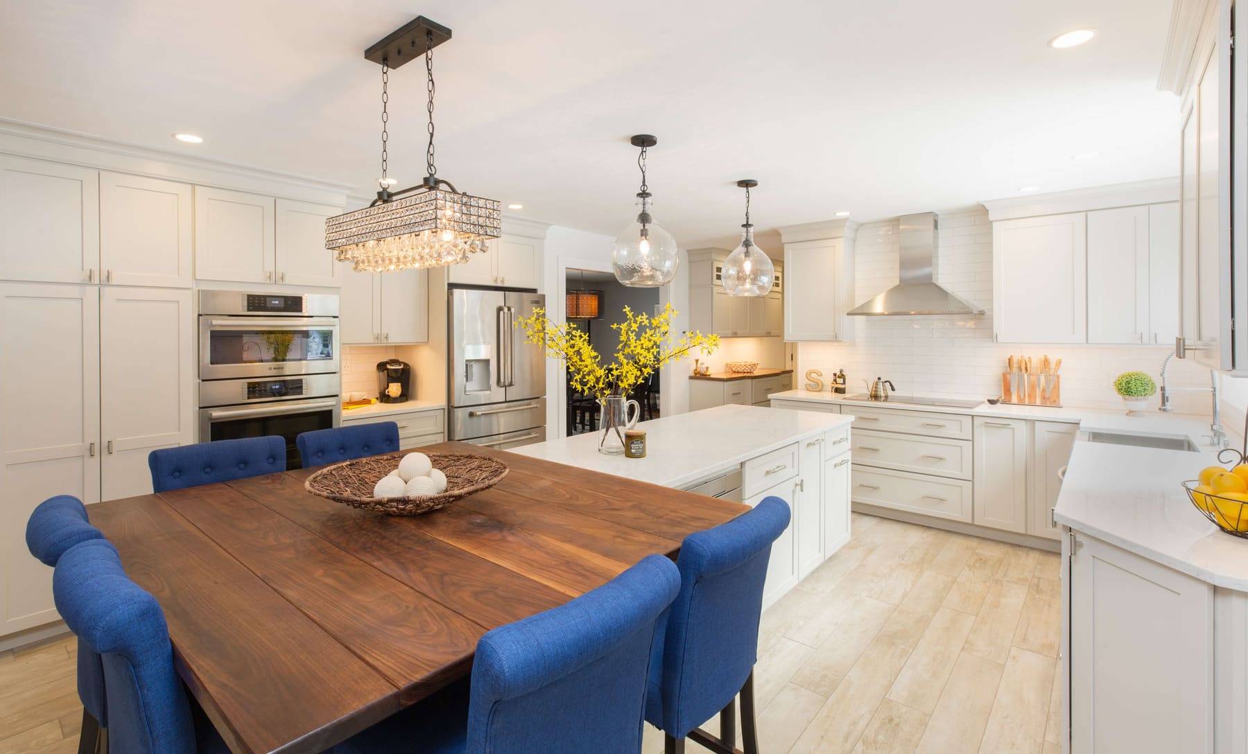 White kitchen with a dark island and blue stools, designed with cabinetry from Plaistow Cabinet
