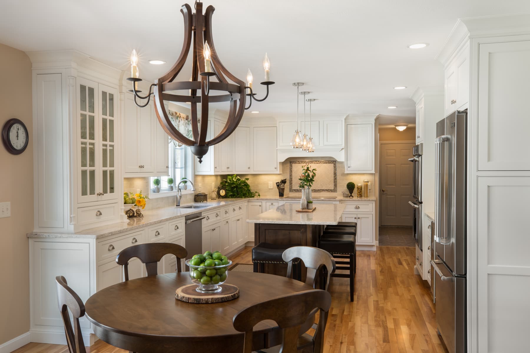 White kitchen cabinetry, dark island, and wood dining chandelier in a Plaistow, New Hampshire home