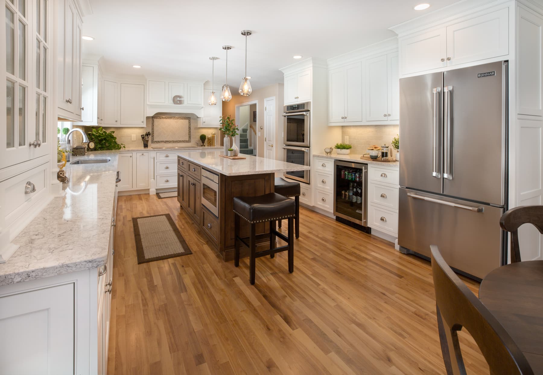 White kitchen cabinetry, dark island, and wood dining chandelier in a Plaistow, New Hampshire home