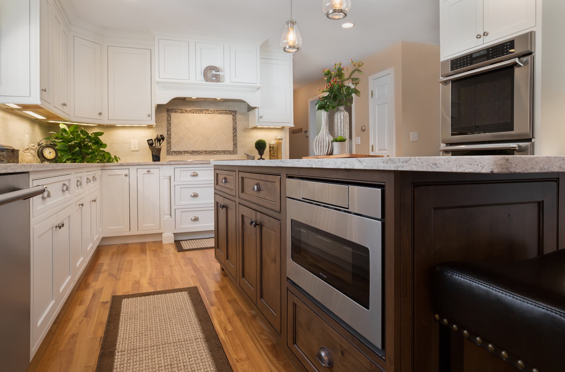 White kitchen cabinetry, dark island, and wood dining chandelier in a Plaistow, New Hampshire home