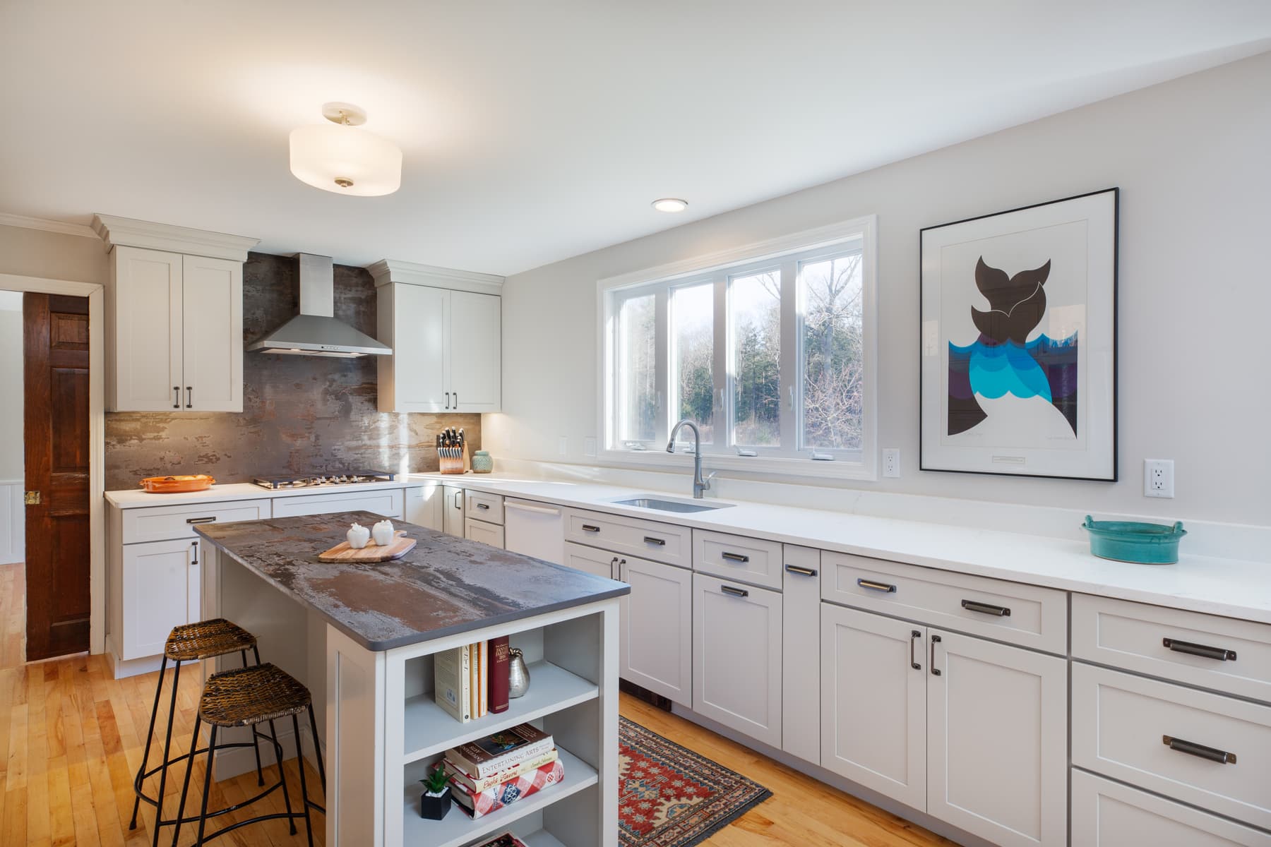 White kitchen cabinetry, quartz counters, and a small island in a Rye, New Hampshire home